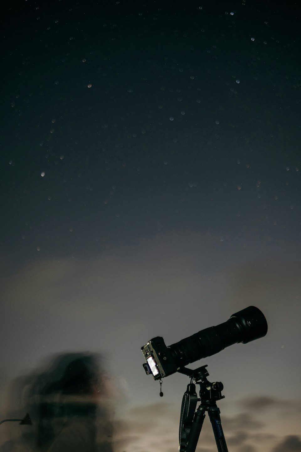 A camera on a tripod pointing at the night sky.