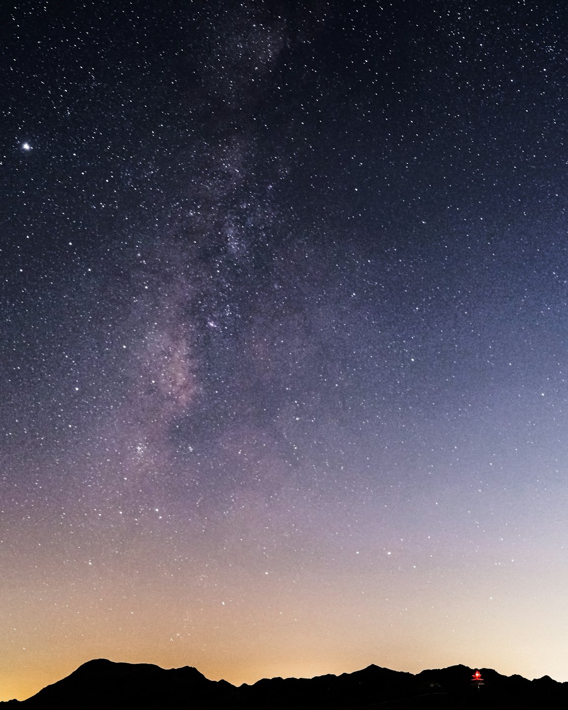 Starry night sky with the Milky Way above a mountain silhouette.